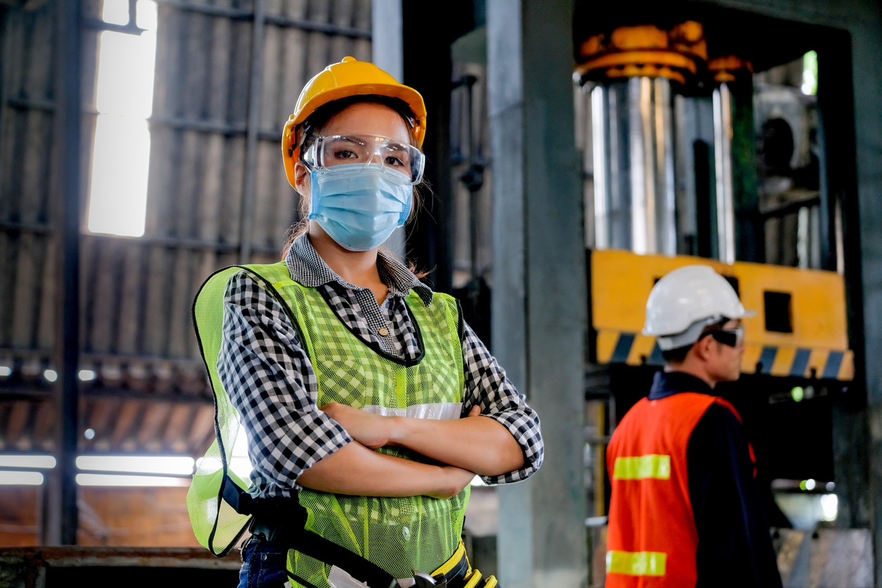 Factory woman worker or technician with hygienic mask stand with confident action with her co-worker as background Masked Construction Worker on Jobsite: New OSHA NEP for COVID-19 Rolled Out in March 2021
